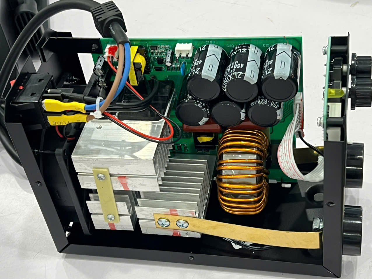 Open electronic power supply enclosure showing capacitors, transformer, heatsinks and wiring used for power regulation inside a metal chassis.