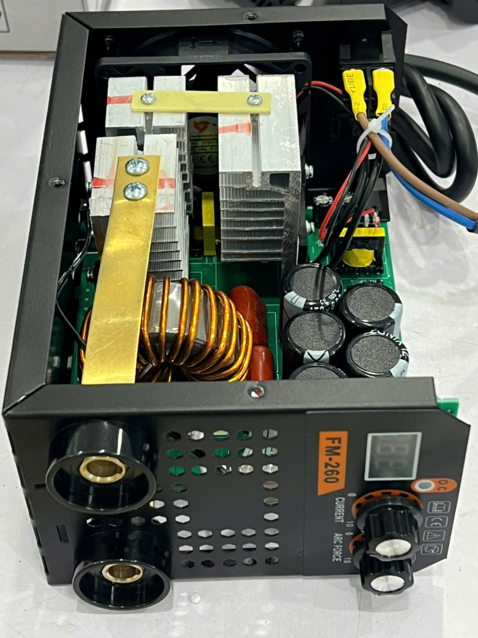 Open-power supply with heat sinks, large copper coil, capacitors, and wiring inside a metal chassis.